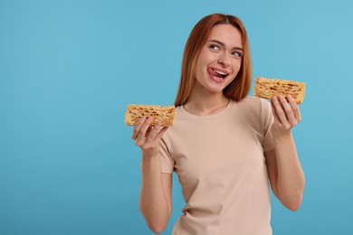 Photo of Young woman with pieces of tasty cake on light blue background, space for text