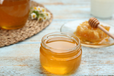 Photo of Tasty honey on light blue wooden table, closeup