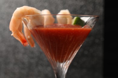 Tasty shrimp cocktail with sauce in glass on grey background, closeup