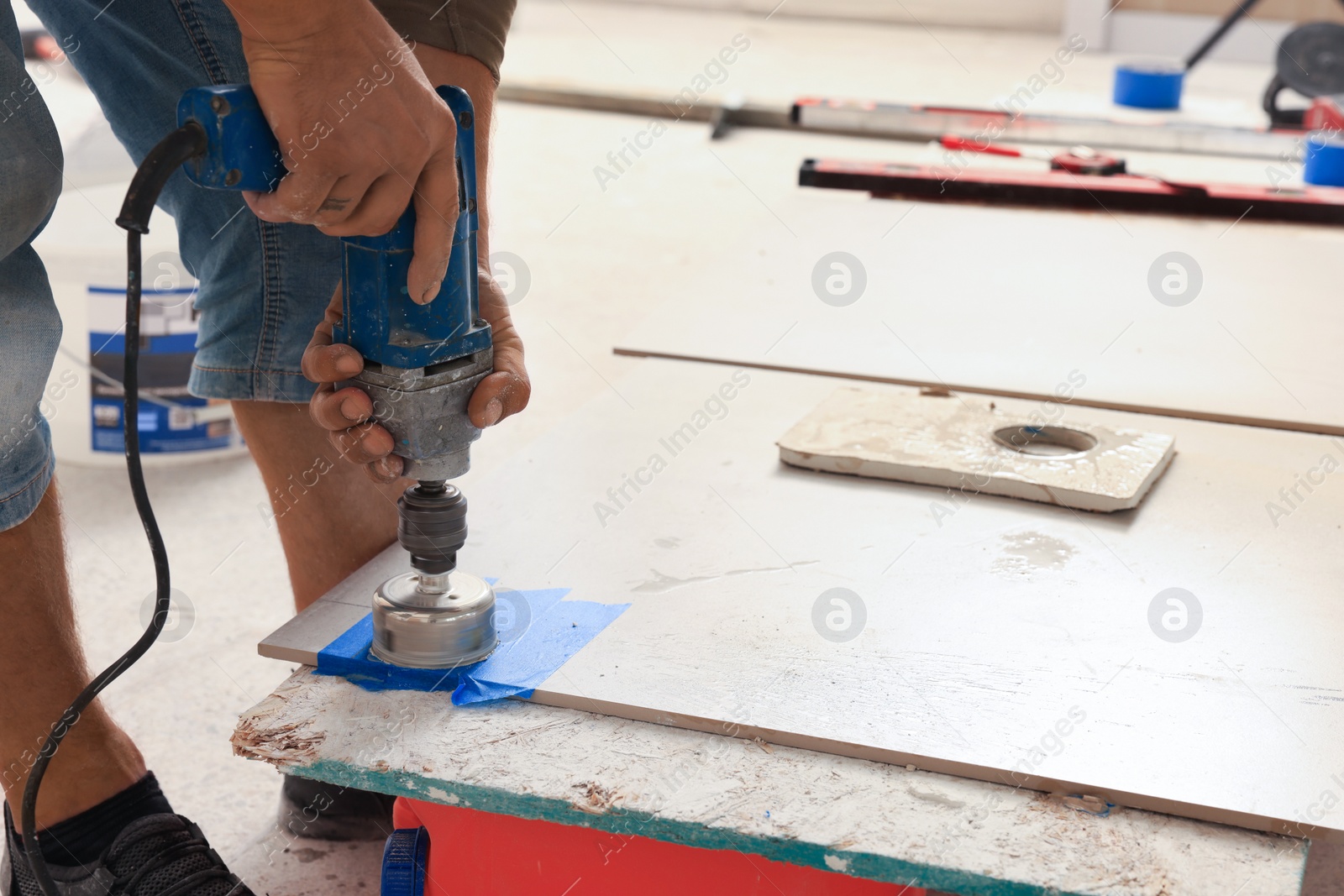 Photo of Worker making socket hole in tile indoors, closeup