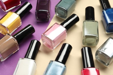 Bright nail polishes in bottles on color background, closeup