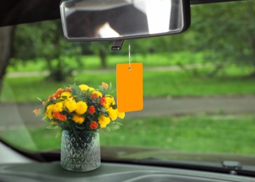 Image of Beautiful flowers and air freshener hanging in car