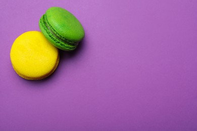 Delicious colorful macarons on purple background, flat lay. Space for text