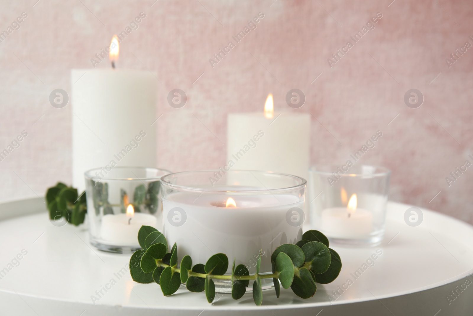 Photo of Composition with burning aromatic candles and eucalyptus on table. Space for text