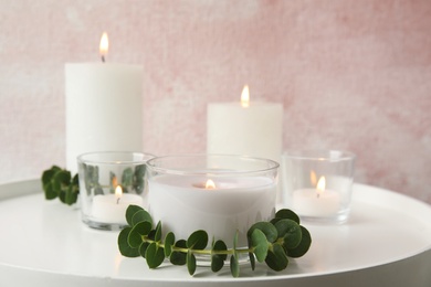 Photo of Composition with burning aromatic candles and eucalyptus on table. Space for text
