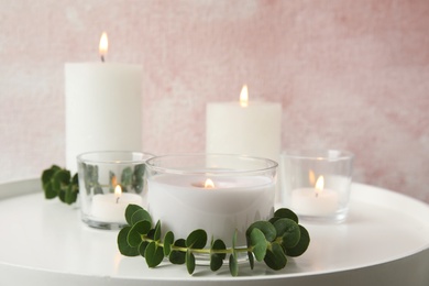 Composition with burning aromatic candles and eucalyptus on table. Space for text