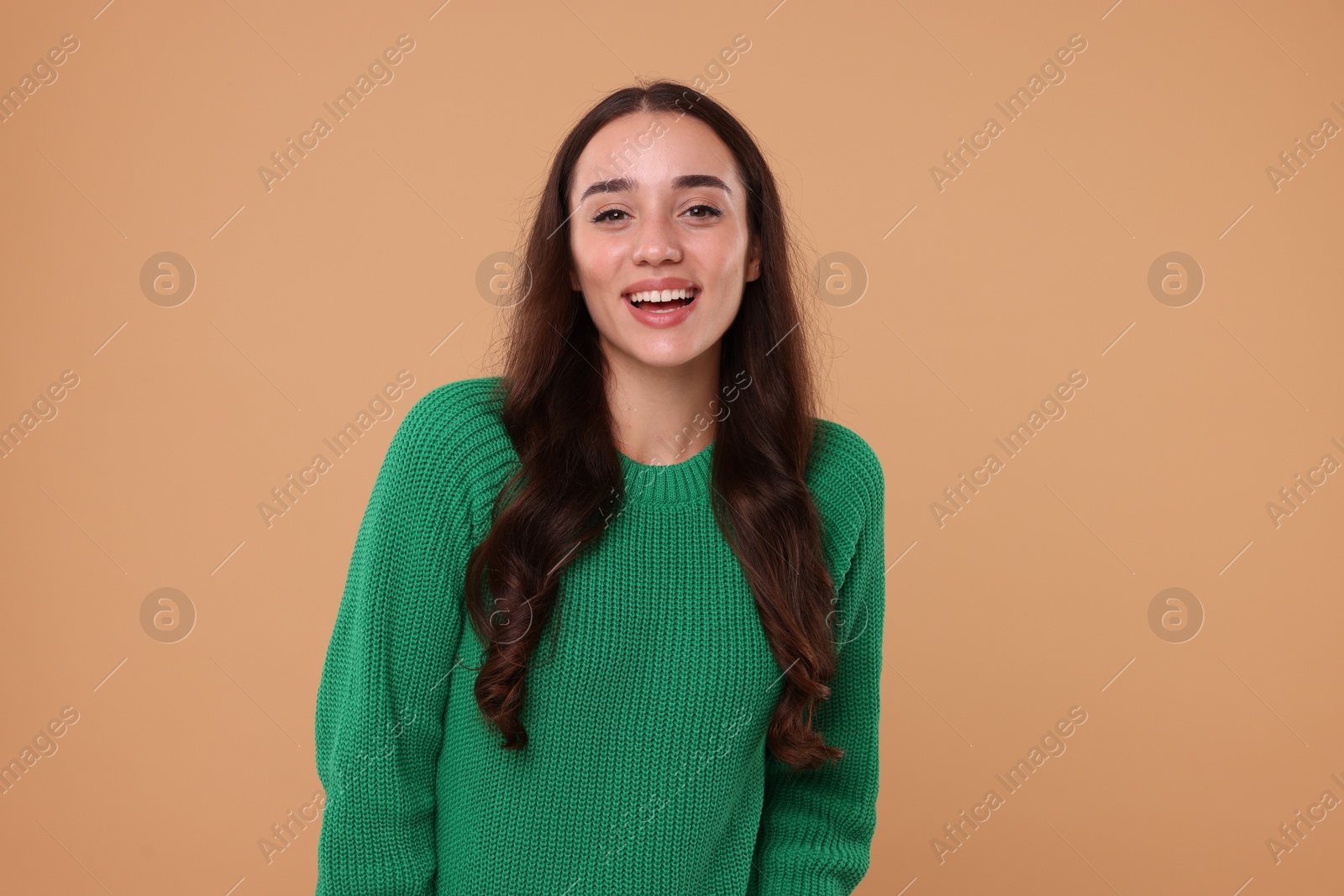 Photo of Beautiful young woman in stylish warm sweater on beige background