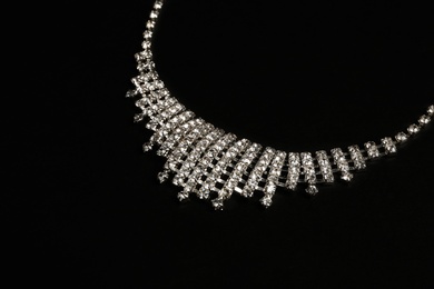 Photo of Stylish necklace with gemstones on black background, closeup. Luxury jewelry