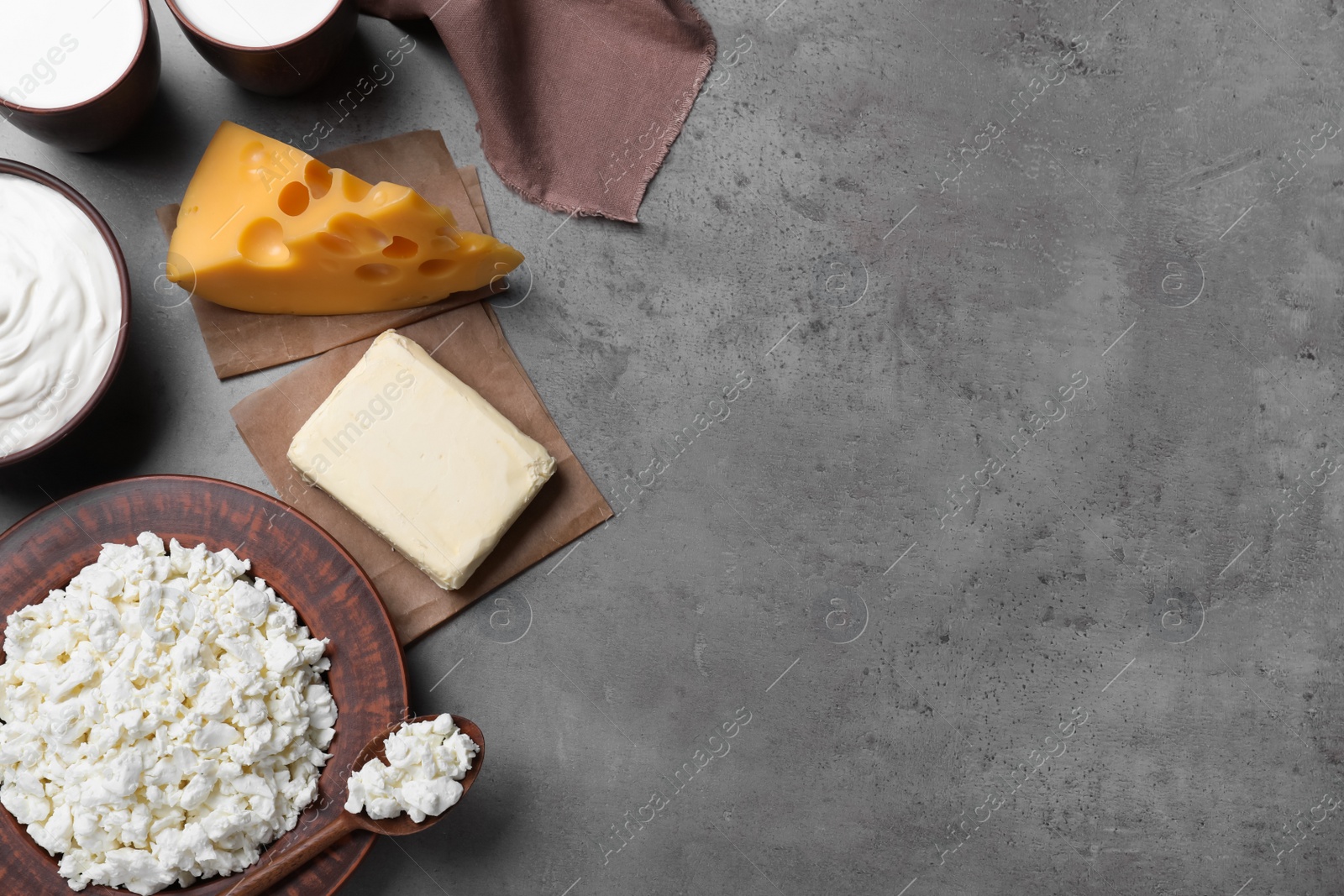 Photo of Clay dishware with fresh dairy products on grey table, flat lay. Space for text