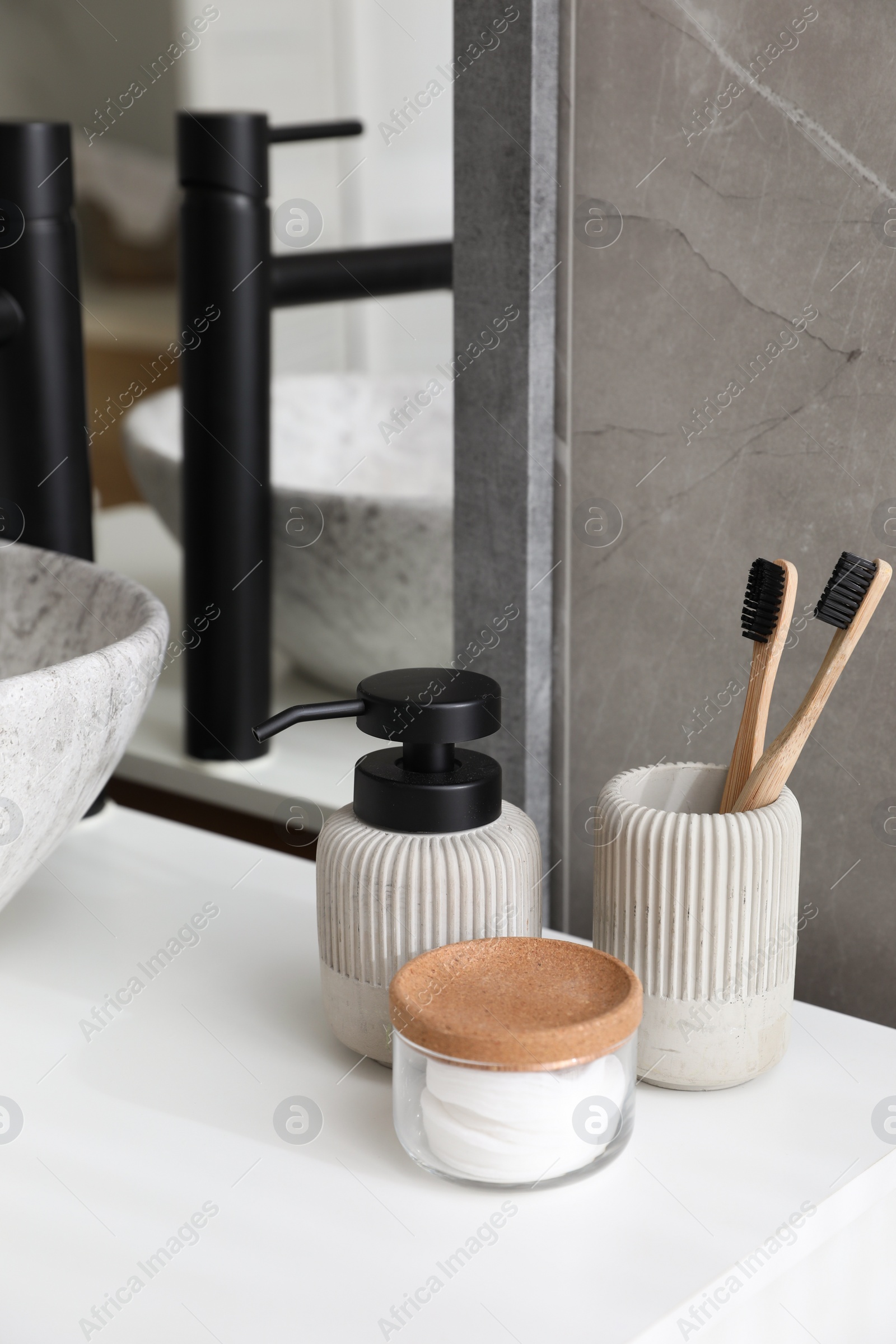 Photo of Stone vessel sink with faucet and toiletries on white countertop in bathroom