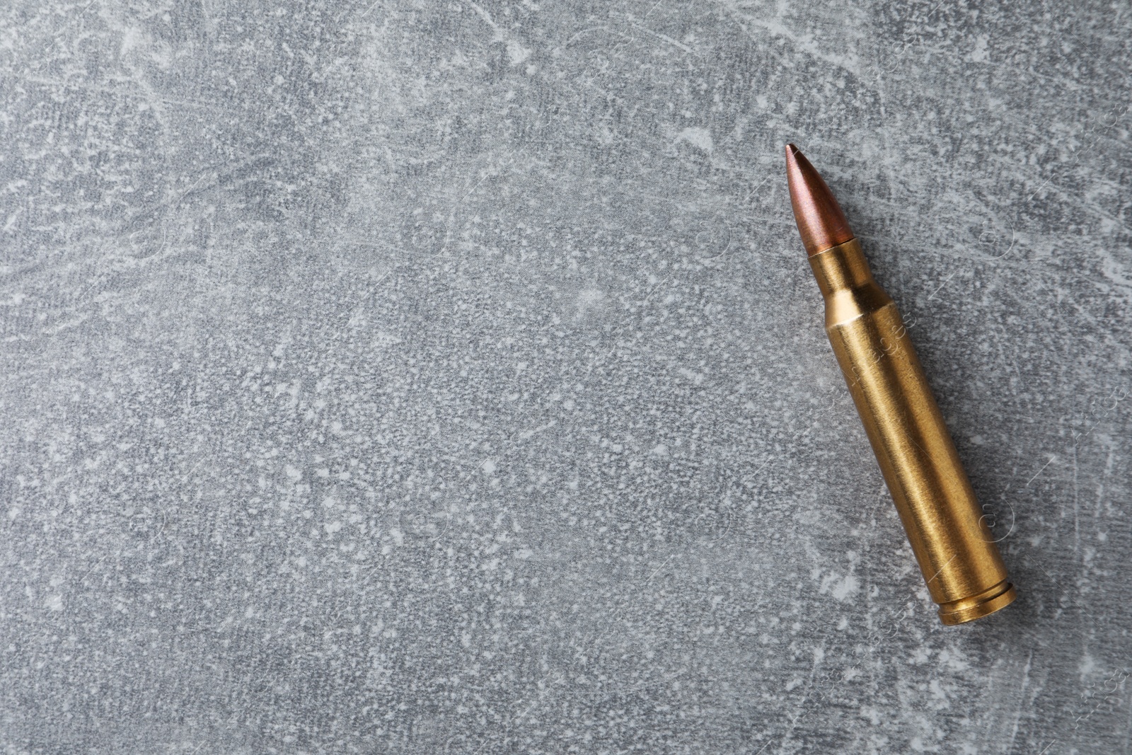 Photo of Bullet on light grey table, top view. Space for text