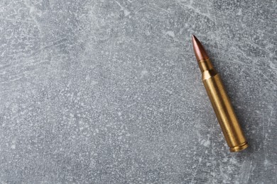 Photo of Bullet on light grey table, top view. Space for text