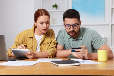 Photo of Couple with credit card using laptop for paying taxes online at home