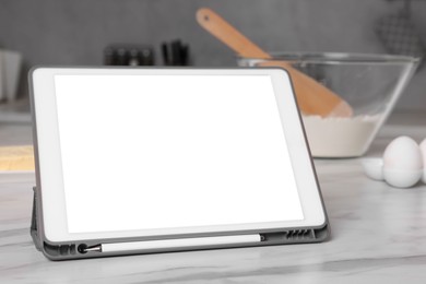 Photo of Modern tablet with blank screen on white marble table in kitchen, closeup