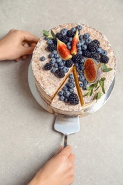 Woman and delicious homemade cake with fresh berries on table, top view