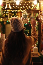 Photo of Young woman spending time at Christmas fair, back view