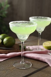 Delicious Margarita cocktail in glasses on wooden table, closeup