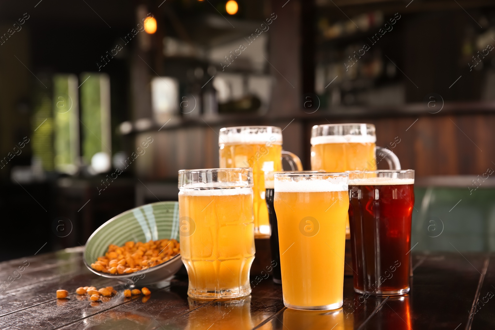 Photo of Glasses of tasty beer on wooden table in bar