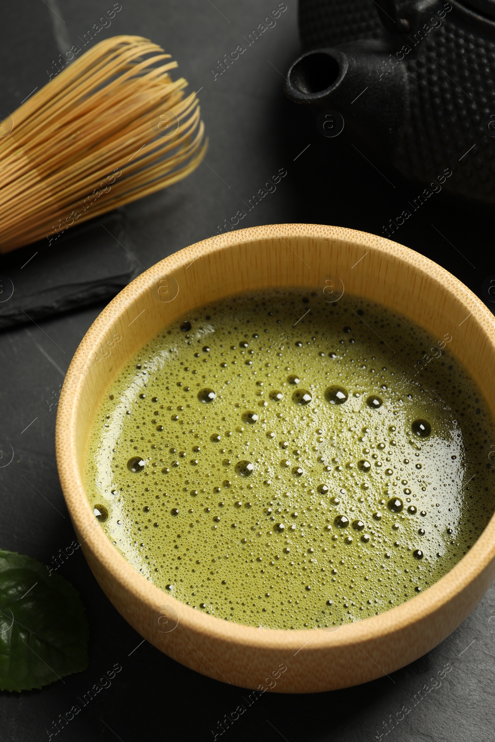 Photo of Cup of fresh matcha tea on black table, closeup