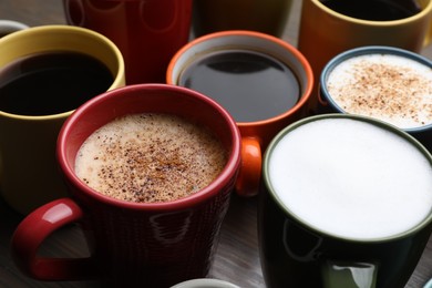 Photo of Many different cups with aromatic hot coffee on table, closeup