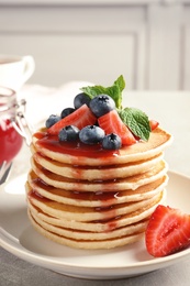 Plate with pancakes and berries on table