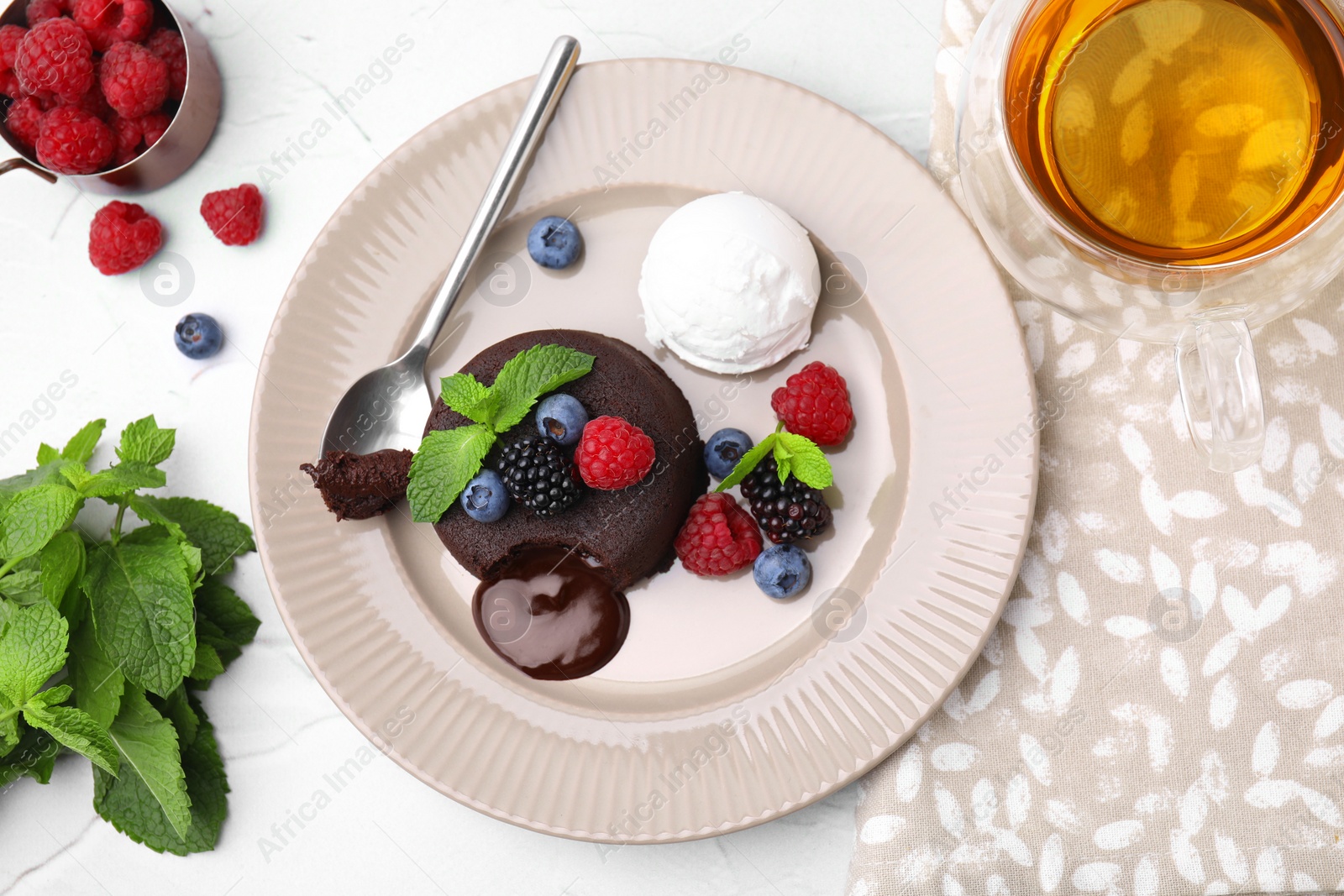 Photo of Delicious chocolate fondant served with fresh berries and ice cream on white table, flat lay