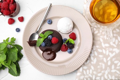 Photo of Delicious chocolate fondant served with fresh berries and ice cream on white table, flat lay