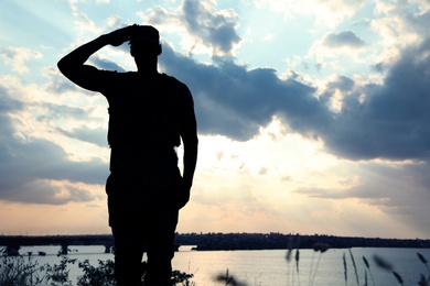 Photo of Soldier in uniform saluting outdoors. Military service