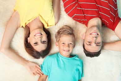 Little boy with mother and father lying on fuzzy rug, top view