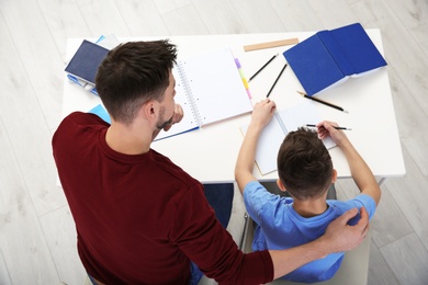 Dad helping his son with homework in room, above view