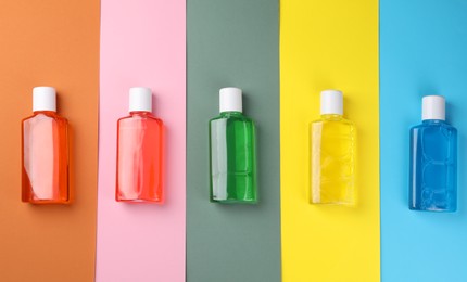 Fresh mouthwashes in bottles on color background, flat lay