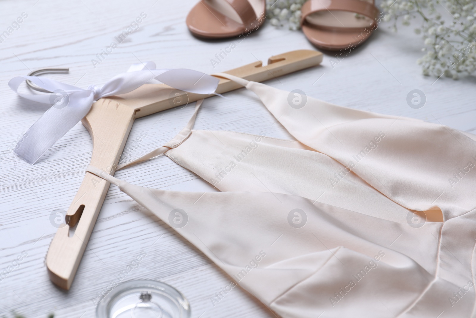 Photo of Beautiful wedding dress and flowers on white wooden background, closeup