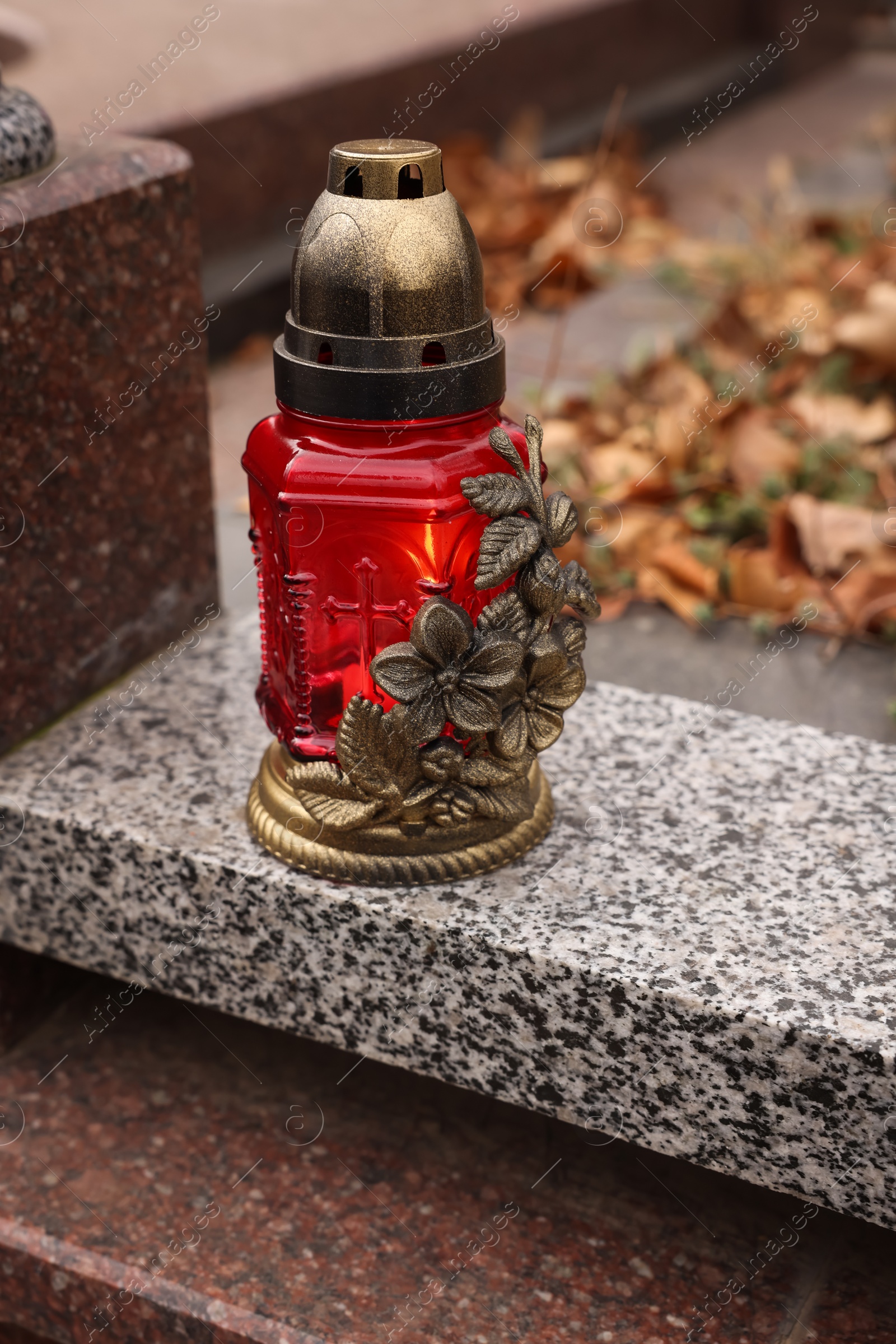 Photo of Grave lantern on grey granite surface at cemetery