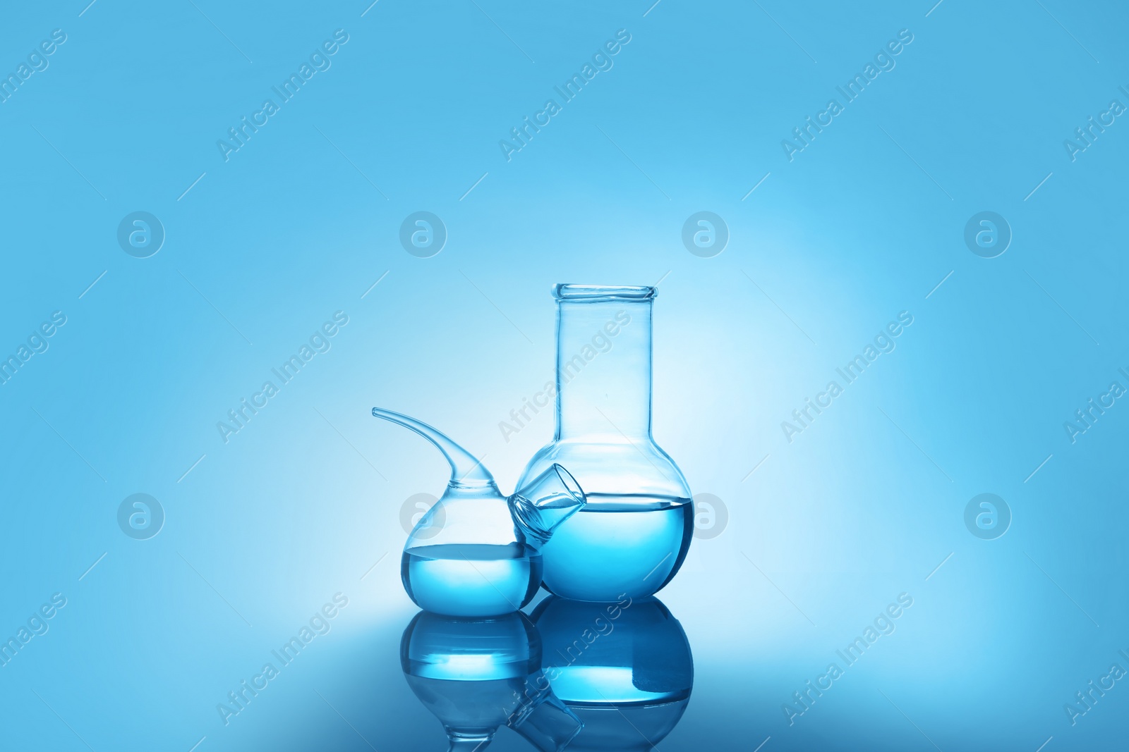 Photo of Laboratory glassware with liquid on table against color background. Chemical analysis