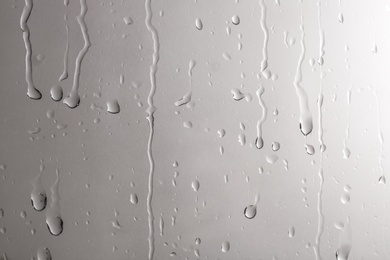 Photo of Glass with rain drops against light background