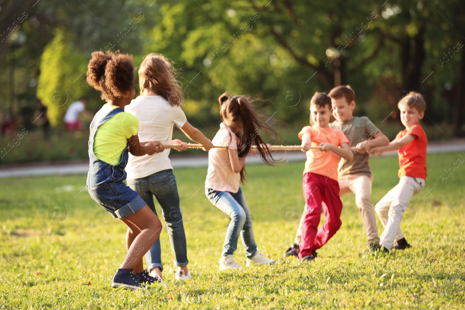 Photo of Cute little children playing with rope outdoors on sunny day