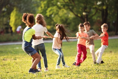 Photo of Cute little children playing with rope outdoors on sunny day