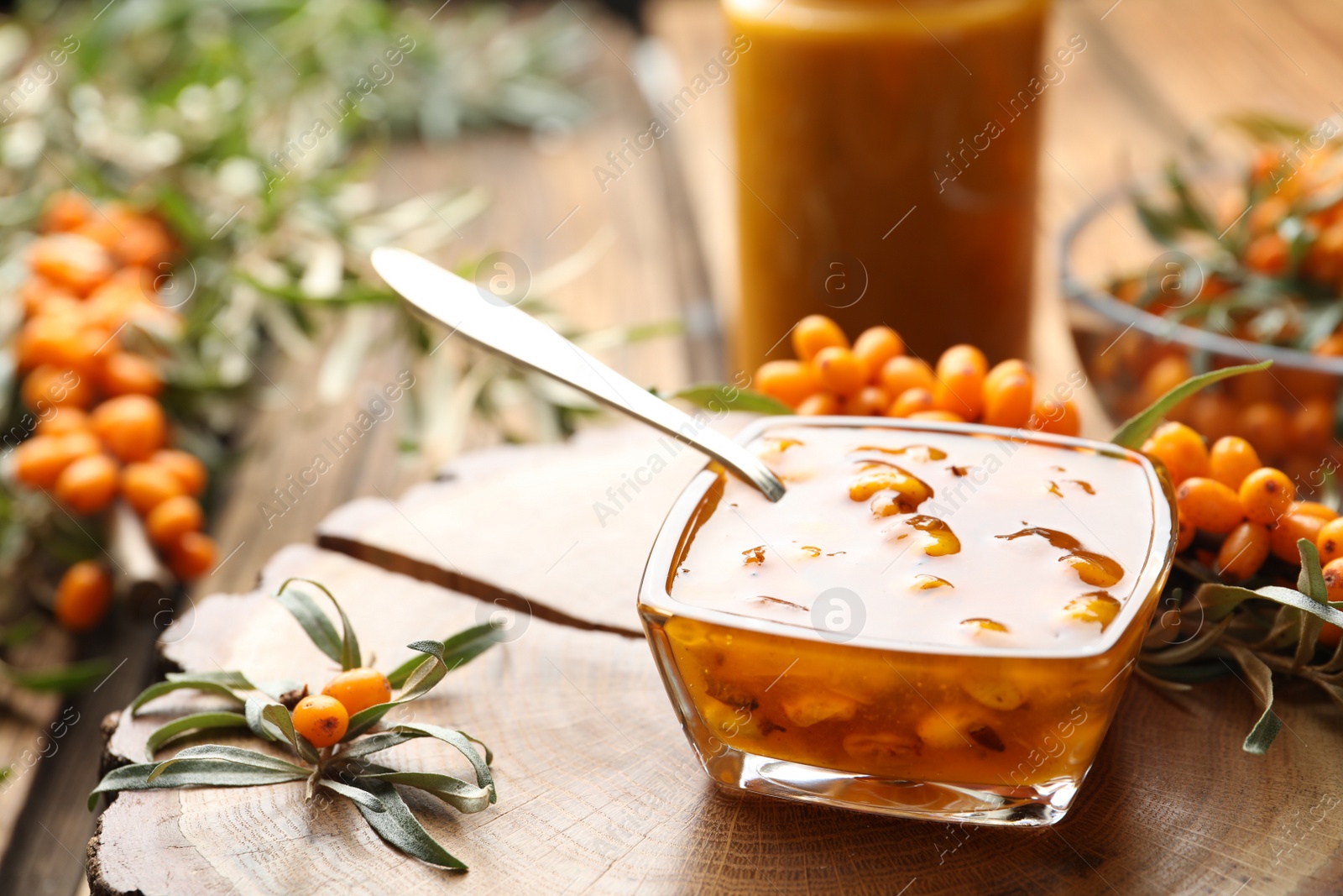 Photo of Delicious sea buckthorn jam and fresh berries on wood. Space for text