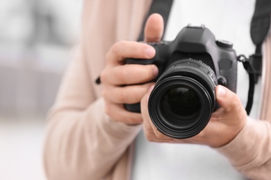 Photo of Male photographer with professional camera on blurred background, closeup