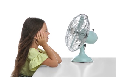 Photo of Little girl enjoying air flow from fan on white background. Summer heat