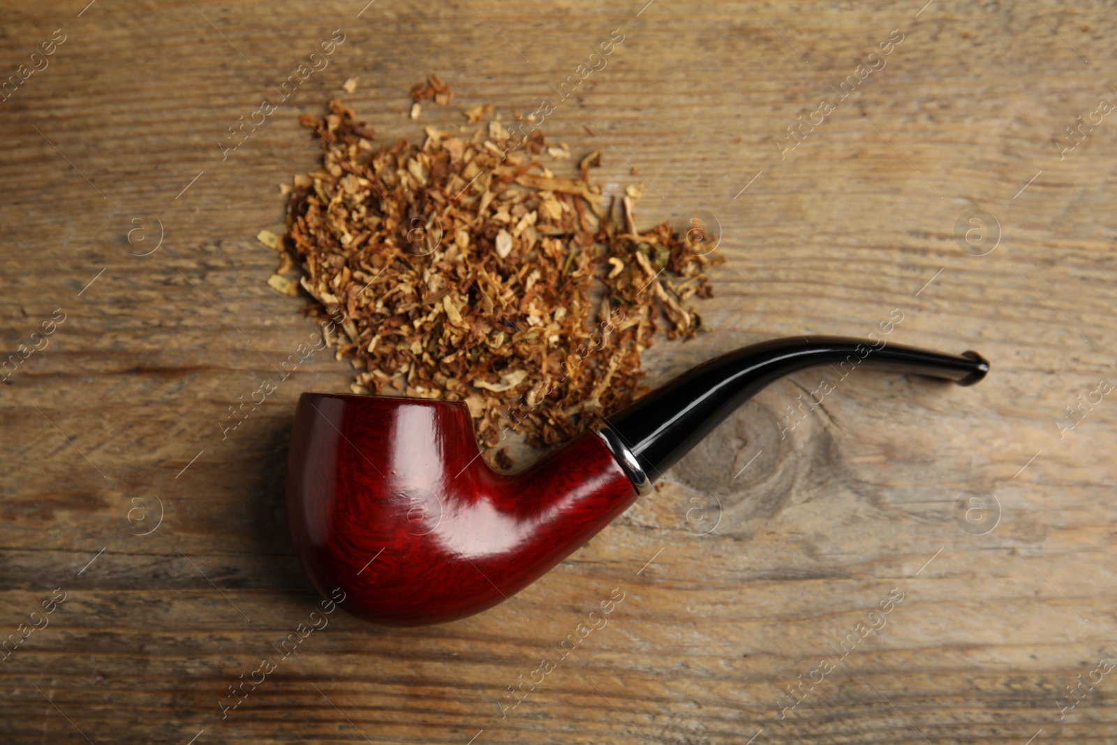 Photo of Classic smoking pipe with tobacco on wooden table, flat lay