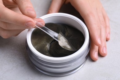 Photo of Woman using under eye patches at light table, closeup. Cosmetic product