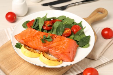 Photo of Tasty grilled salmon with basil, tomatoes and lemon on table