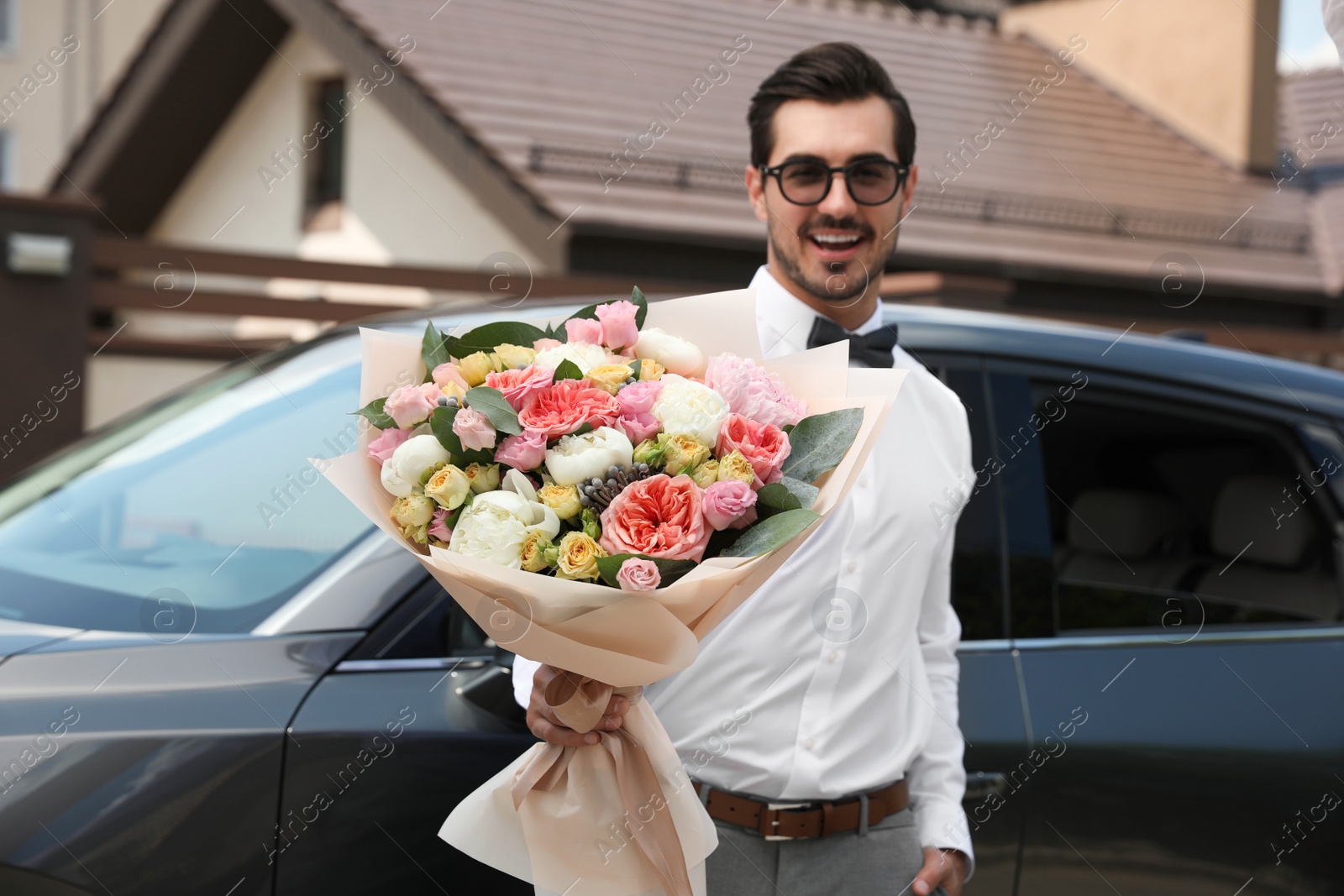 Photo of Young handsome man with beautiful flower bouquet near car outdoors