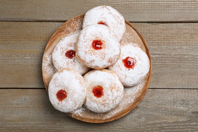 Delicious donuts with jelly and powdered sugar on wooden table, top view