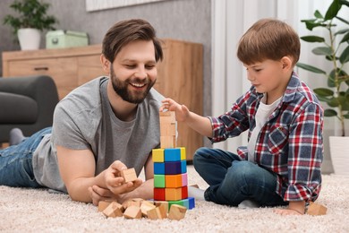 Photo of Happy dad and son building tower with cubes at home