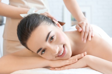 Young woman having body scrubbing procedure with sea salt in spa salon