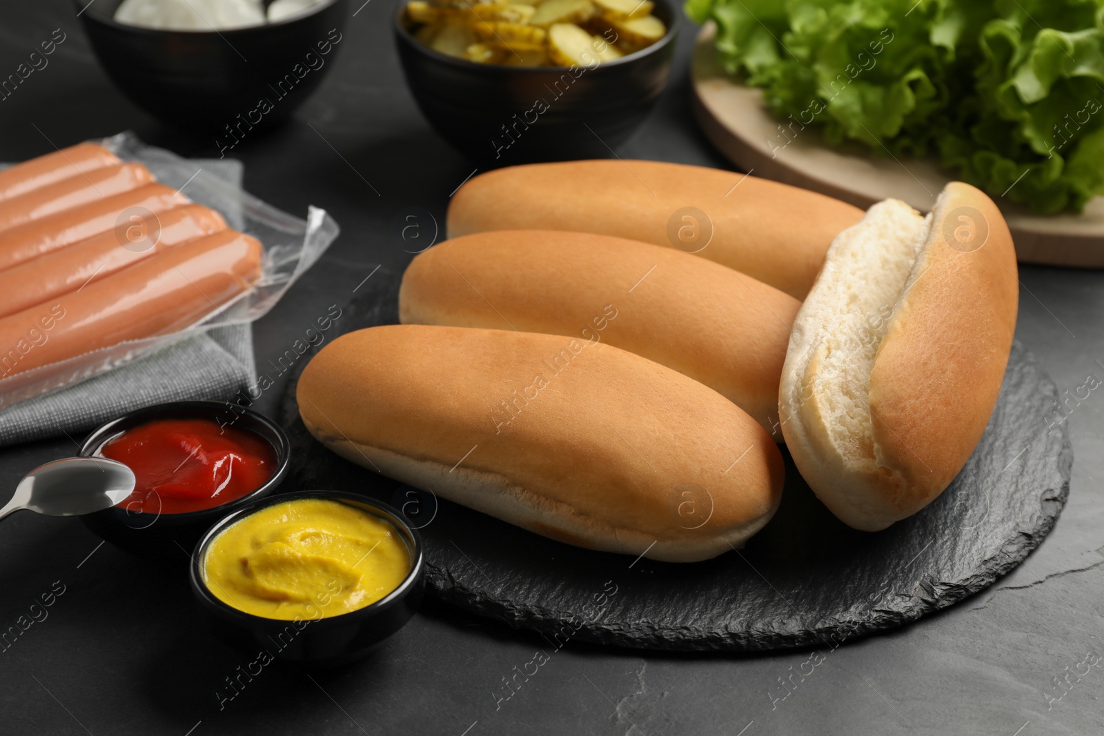 Photo of Different tasty ingredients for hot dog on dark table