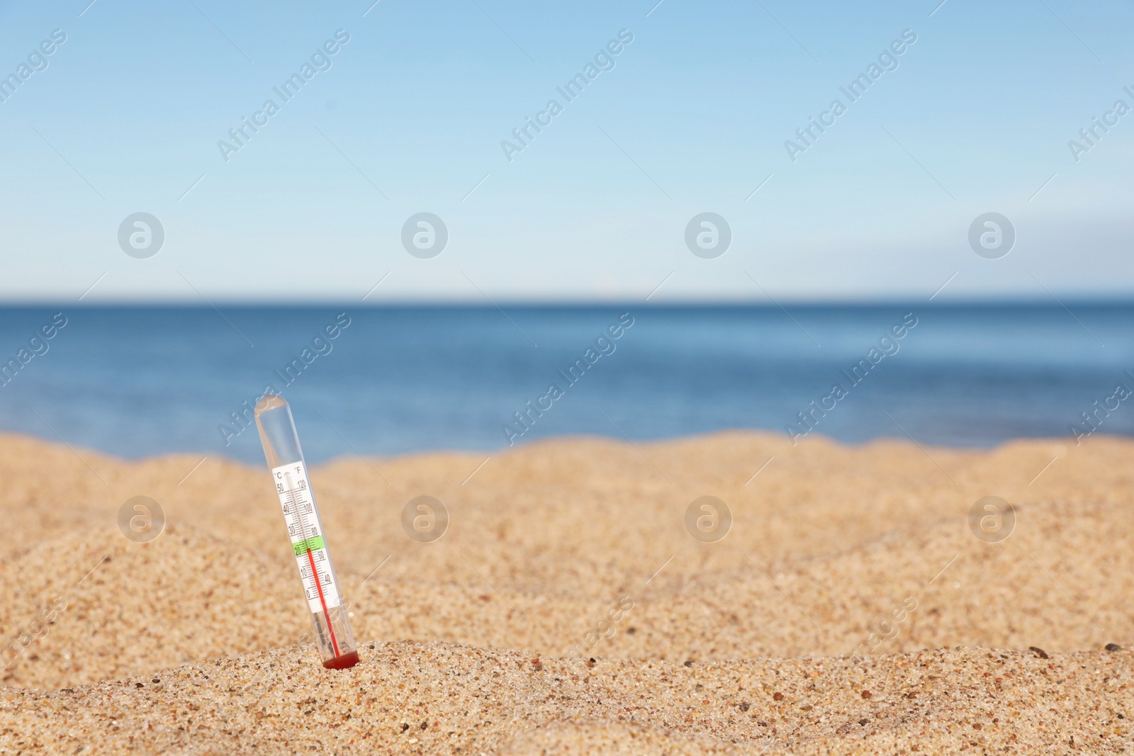 Photo of Weather thermometer in sand near sea, space for text