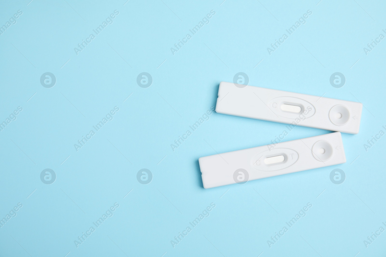 Photo of Two disposable express hepatitis tests on light blue background, flat lay. Space for text